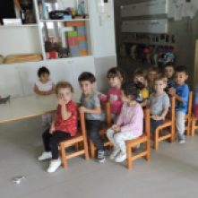 Els infants han col·locat les cadires en forma de tren i estan asseguts jugant